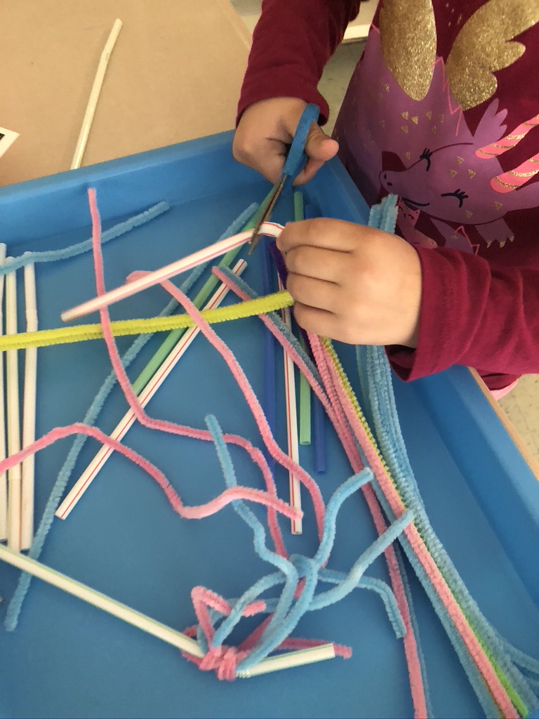 kindergarten child cutting straws with scissors