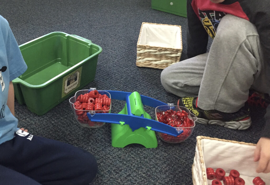 children experiment with balance scale during play centers